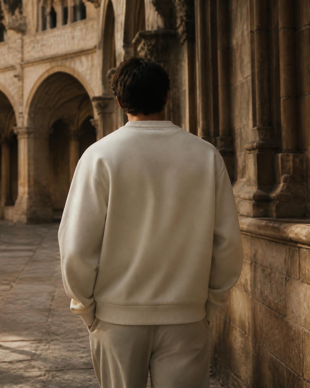 Person in a cream crewneck walking through a stone cloister